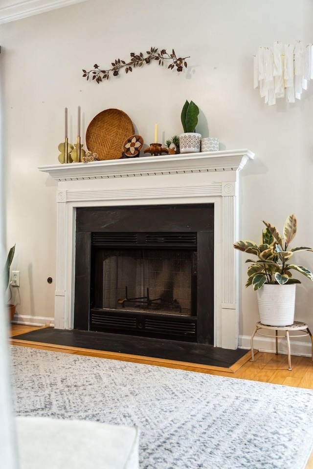 detailed view of a fireplace with flush hearth, baseboards, and wood finished floors