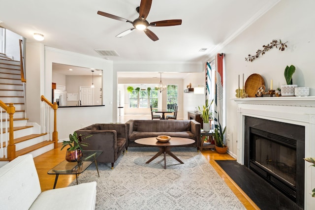 living room with stairway, wood finished floors, crown molding, a ceiling fan, and baseboards