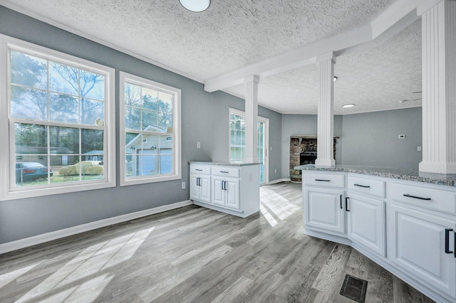 kitchen with light wood-style flooring, a fireplace, visible vents, and white cabinets