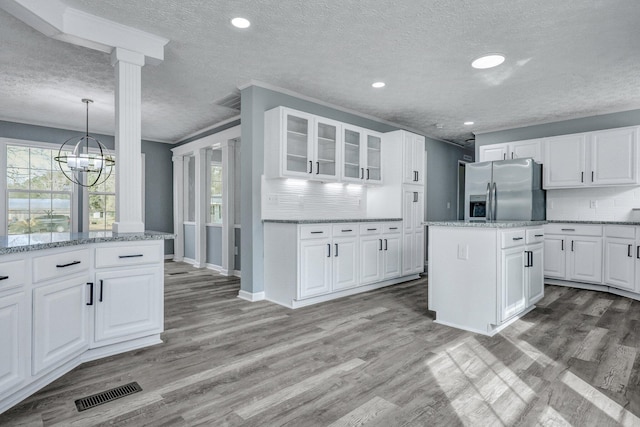 kitchen featuring stainless steel fridge, visible vents, backsplash, and wood finished floors