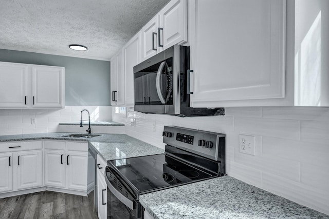 kitchen featuring light stone counters, appliances with stainless steel finishes, white cabinets, and a sink