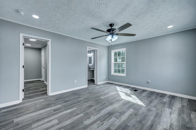 unfurnished bedroom with ornamental molding, a textured ceiling, baseboards, and wood finished floors