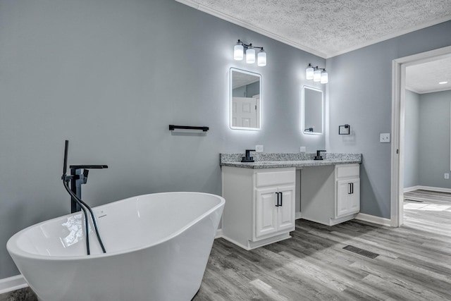 full bathroom featuring a textured ceiling, wood finished floors, visible vents, vanity, and ornamental molding