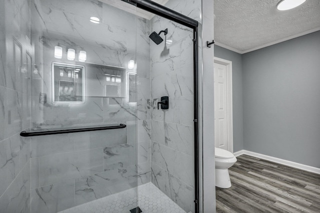 bathroom with a textured ceiling, toilet, wood finished floors, baseboards, and a marble finish shower