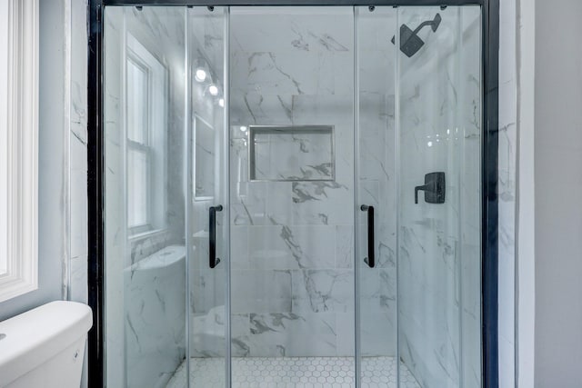 bathroom with toilet and a marble finish shower