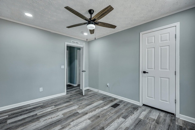 unfurnished bedroom with visible vents, a textured ceiling, baseboards, and wood finished floors