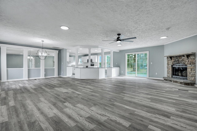 unfurnished living room featuring baseboards, wood finished floors, a textured ceiling, a fireplace, and ceiling fan with notable chandelier