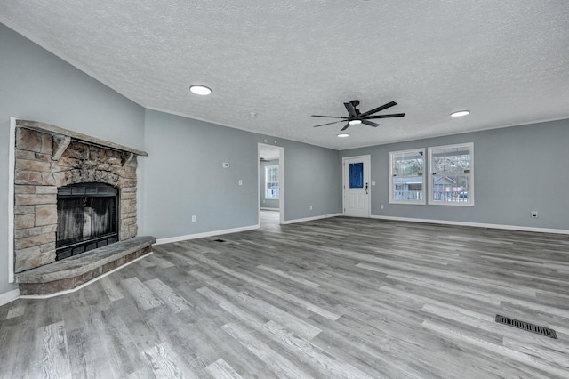 unfurnished living room featuring visible vents, a fireplace, baseboards, and wood finished floors