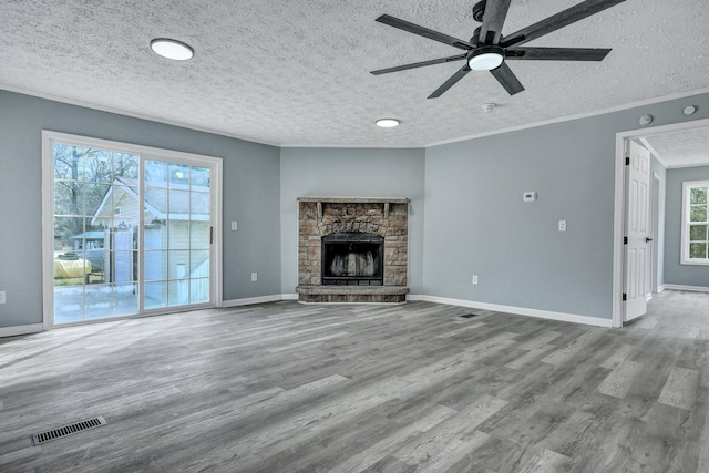 unfurnished living room featuring visible vents, crown molding, a stone fireplace, and wood finished floors