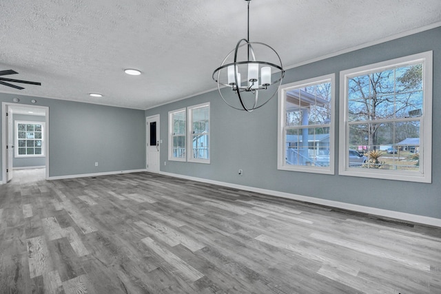 interior space with a textured ceiling, baseboards, wood finished floors, and ornamental molding