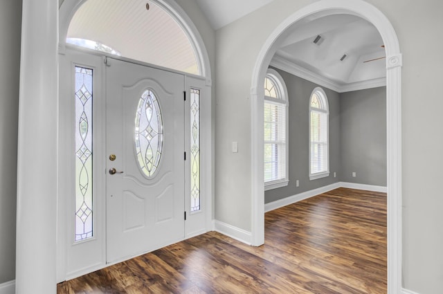 foyer with dark hardwood / wood-style floors, vaulted ceiling, and ornamental molding