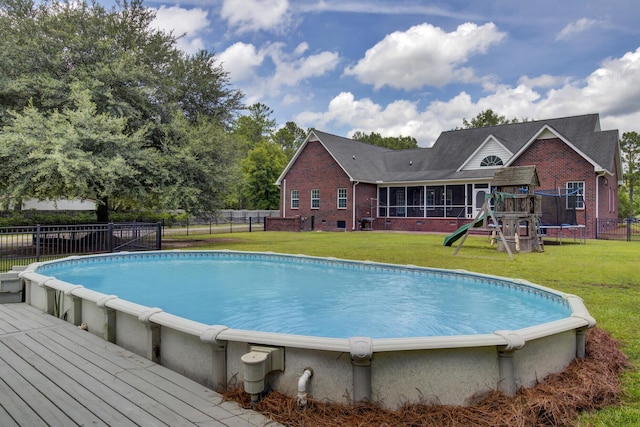 view of pool featuring a playground, a sunroom, a yard, and a trampoline