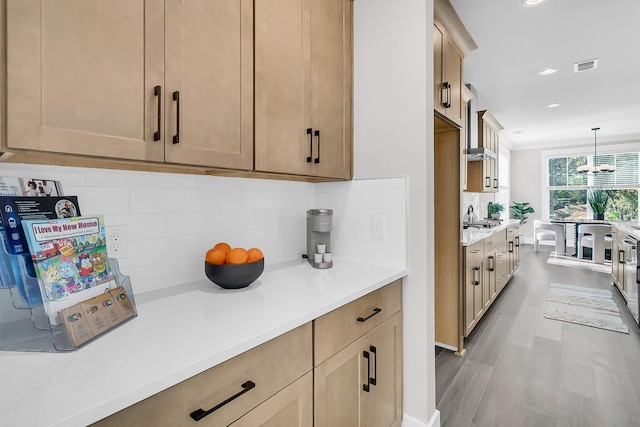 kitchen with hardwood / wood-style flooring, backsplash, decorative light fixtures, stainless steel gas stovetop, and light brown cabinets