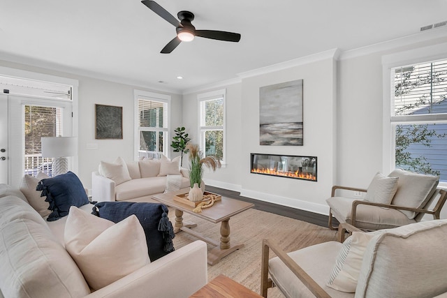 living room featuring crown molding, plenty of natural light, and light hardwood / wood-style floors