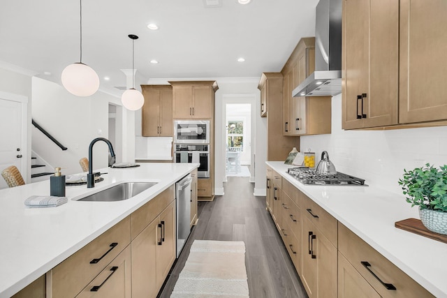 kitchen with wall chimney range hood, sink, hanging light fixtures, stainless steel appliances, and decorative backsplash