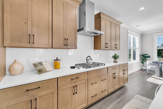 kitchen featuring wall chimney exhaust hood, stainless steel gas cooktop, crown molding, hardwood / wood-style floors, and backsplash