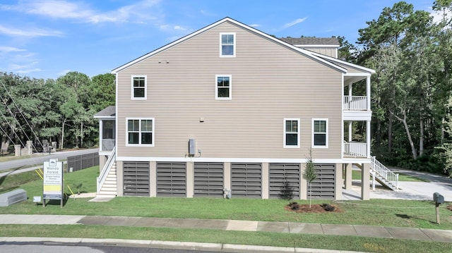 view of side of property with a balcony and a lawn