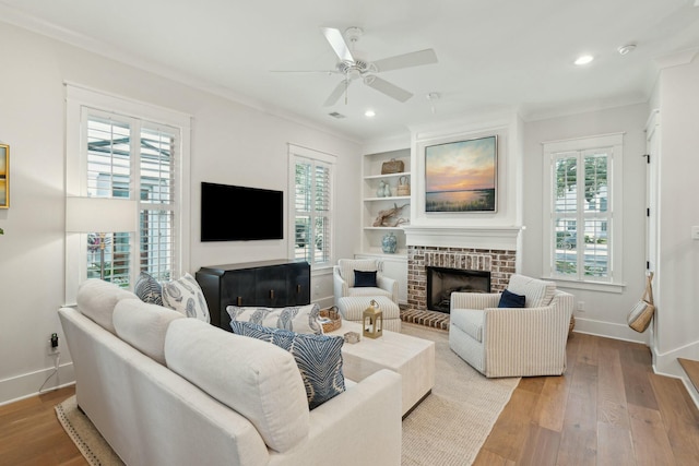 living room featuring light wood finished floors, a healthy amount of sunlight, crown molding, and a ceiling fan