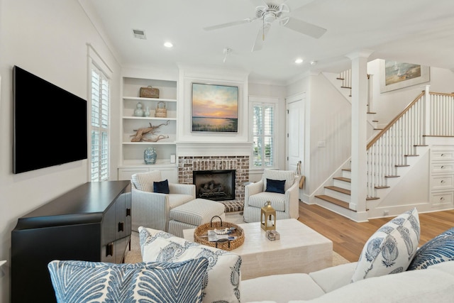 living area with light wood-type flooring, visible vents, built in features, ceiling fan, and stairs