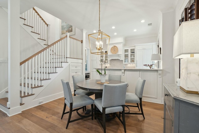 dining area featuring recessed lighting, stairs, an inviting chandelier, and wood finished floors