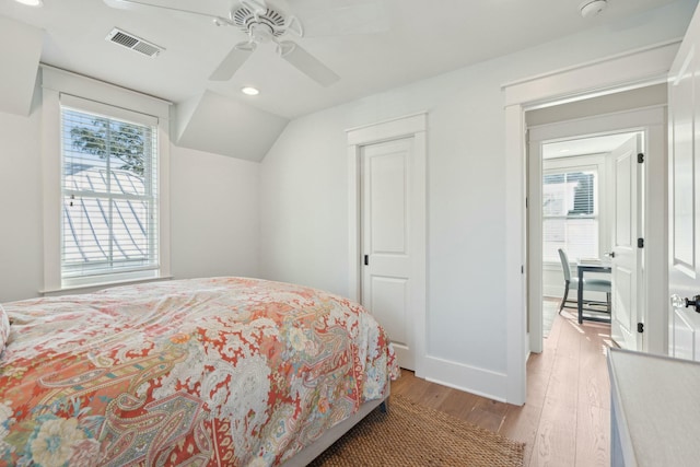 bedroom featuring a ceiling fan, baseboards, visible vents, light wood-style flooring, and vaulted ceiling