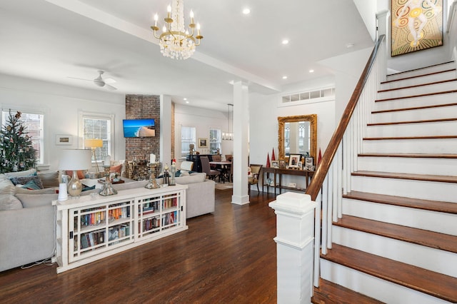 living room with dark hardwood / wood-style flooring and ceiling fan with notable chandelier