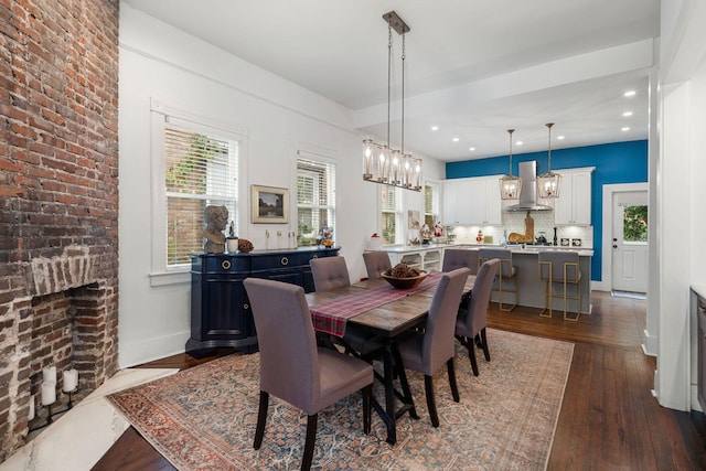 dining area with plenty of natural light, dark wood-type flooring, and a brick fireplace