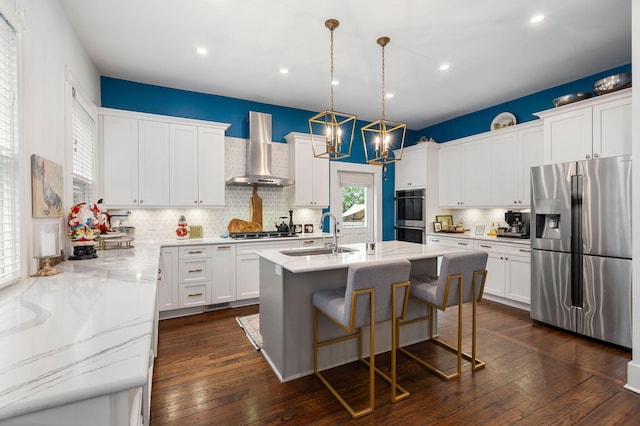 kitchen with white cabinets, sink, wall chimney range hood, and stainless steel appliances