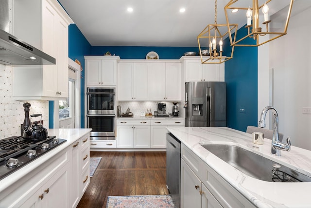 kitchen with wall chimney exhaust hood, white cabinetry, sink, and appliances with stainless steel finishes