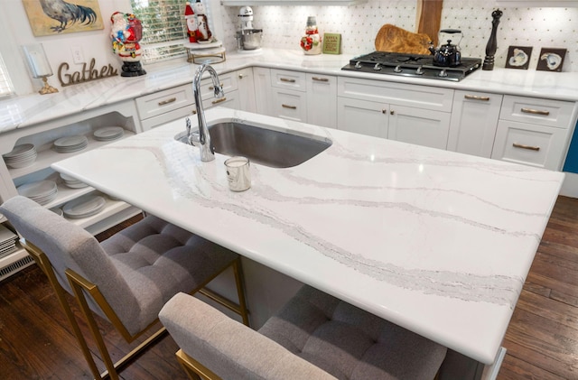 kitchen featuring white cabinetry, sink, dark wood-type flooring, stainless steel gas cooktop, and decorative backsplash