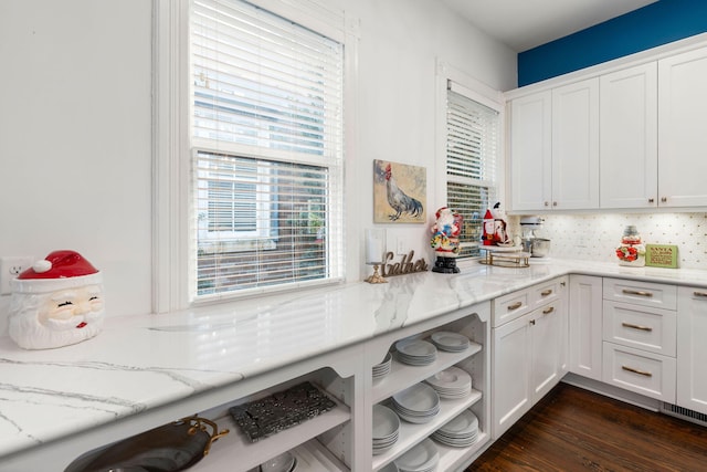 kitchen featuring dark hardwood / wood-style floors, white cabinetry, tasteful backsplash, and light stone counters