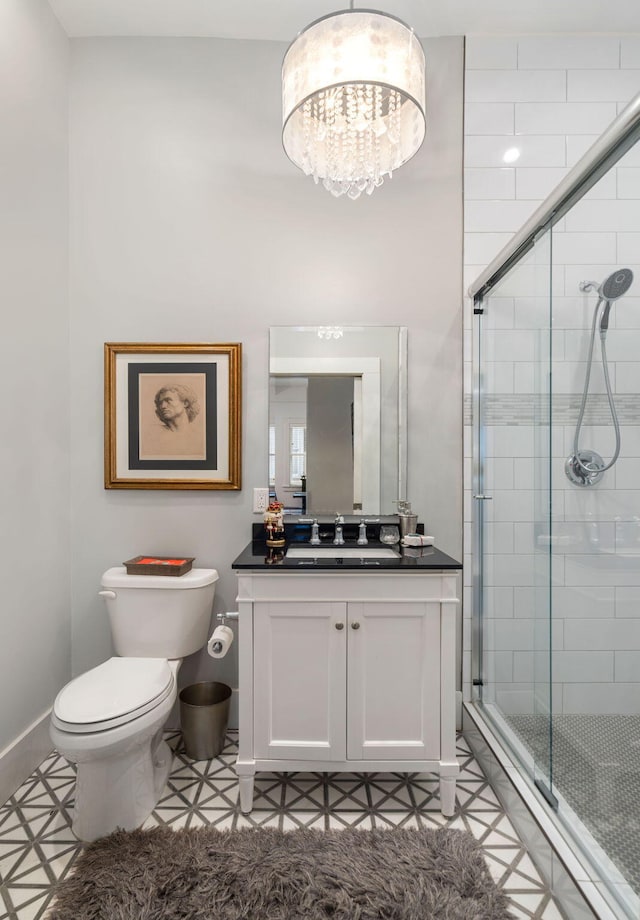 bathroom with tile patterned flooring, vanity, toilet, and a shower with shower door