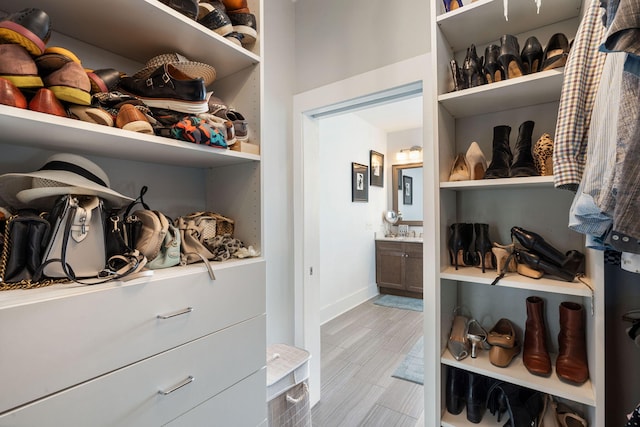 walk in closet with light hardwood / wood-style flooring