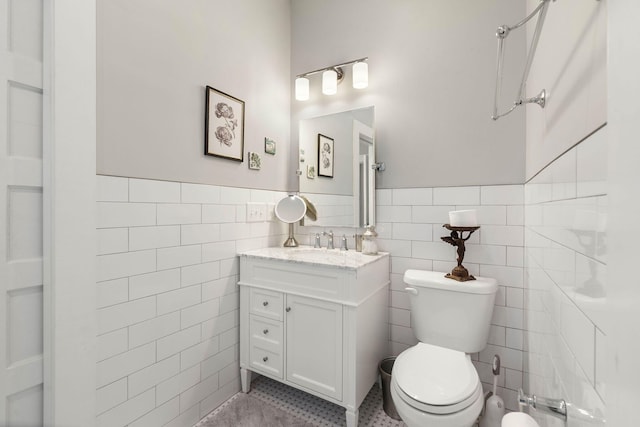 bathroom with tile patterned floors, vanity, tile walls, and toilet