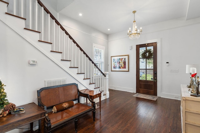 foyer with a notable chandelier, plenty of natural light, and dark wood-type flooring