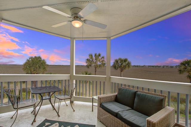 balcony at dusk featuring a ceiling fan, outdoor lounge area, and a rural view