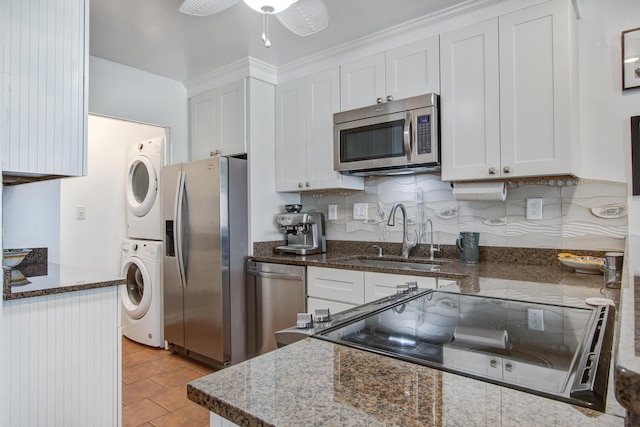 kitchen with a ceiling fan, a sink, stainless steel appliances, white cabinets, and stacked washer / drying machine