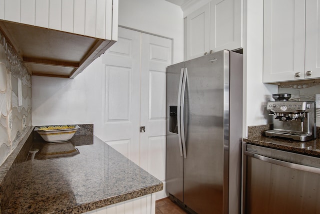 kitchen with white cabinetry, dark stone countertops, and stainless steel fridge