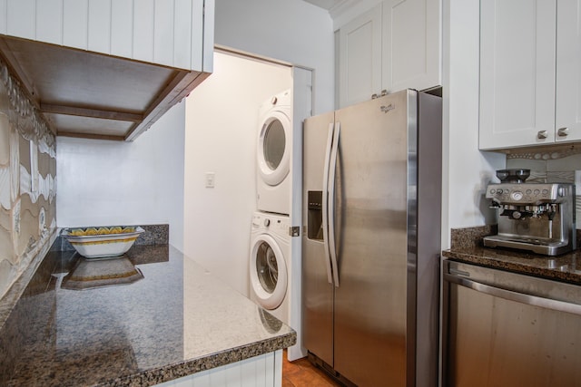 kitchen with dark countertops, white cabinets, stainless steel fridge, and stacked washing maching and dryer