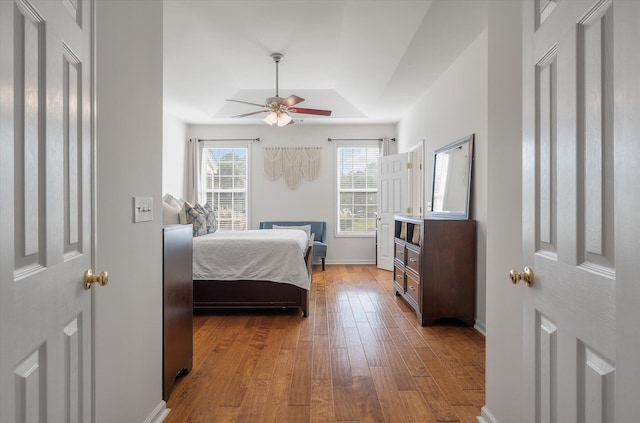 bedroom featuring ceiling fan, hardwood / wood-style flooring, and a tray ceiling