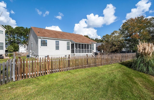 rear view of house with a yard and a sunroom