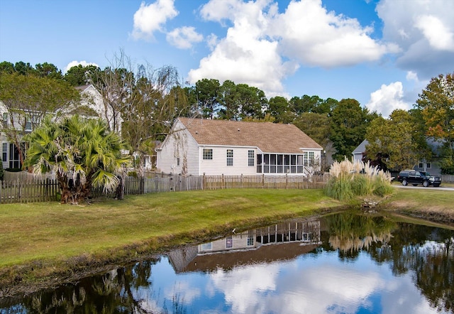 rear view of property with a water view, a sunroom, and a yard