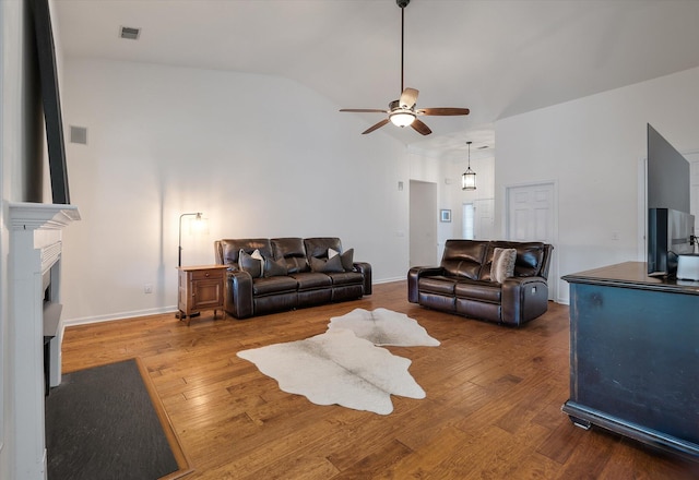 living room with ceiling fan, hardwood / wood-style flooring, lofted ceiling, and a fireplace