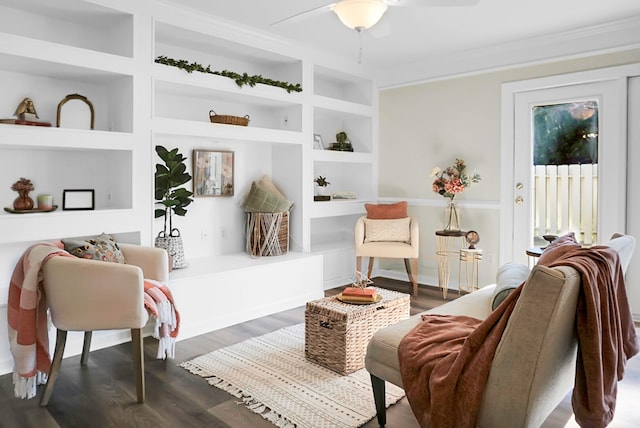 sitting room with built in shelves, dark hardwood / wood-style flooring, and ceiling fan