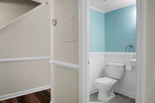 bathroom featuring tile patterned flooring, ornamental molding, and toilet