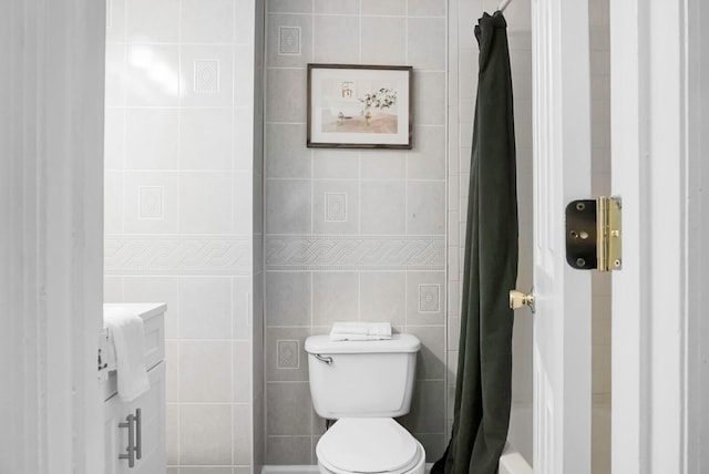 bathroom featuring tile walls, toilet, and a shower with shower curtain