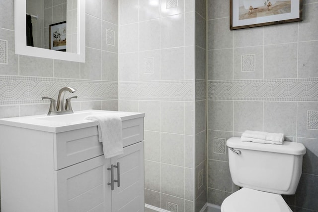 bathroom with tile walls, vanity, and toilet