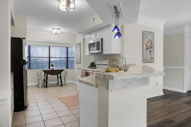 kitchen with hanging light fixtures, white cabinetry, kitchen peninsula, stainless steel appliances, and crown molding