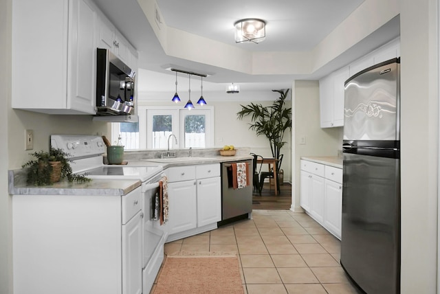 kitchen with appliances with stainless steel finishes, hanging light fixtures, sink, and white cabinetry