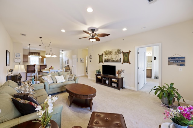 living room with ceiling fan with notable chandelier and light carpet